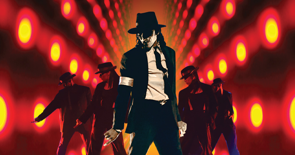 A person in a black trilby, white shirt, and black suit strikes a dance pose in front of four similarly dressed dancers, with a vibrant background of glowing red and yellow lights forming a tunnel effect.