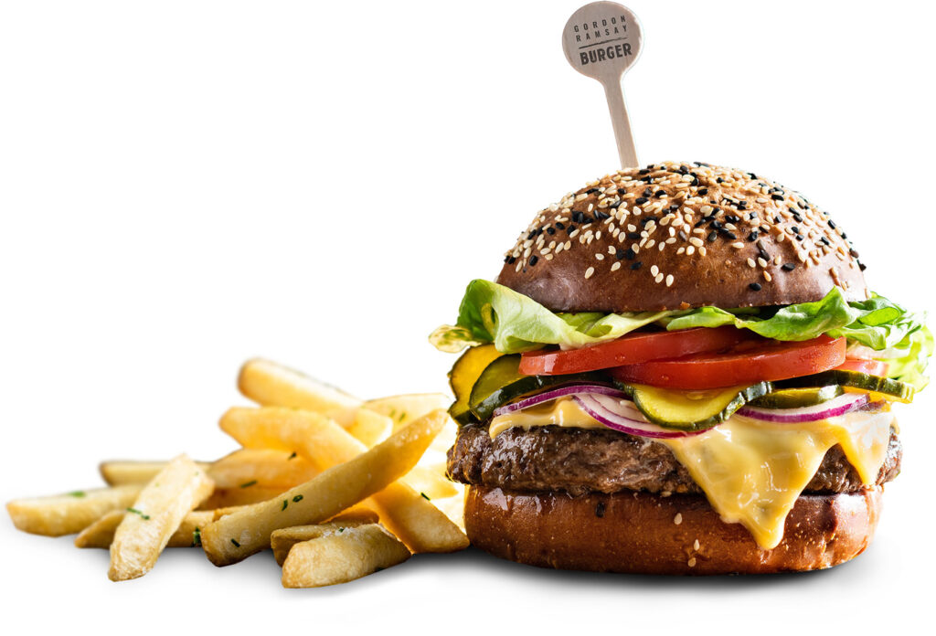 A cheeseburger with lettuce, tomato, gherkins, red onion, and melted cheese on a sesame bun, served with a side of chips—perfect for enjoying during your visit to Casino Vancouver.